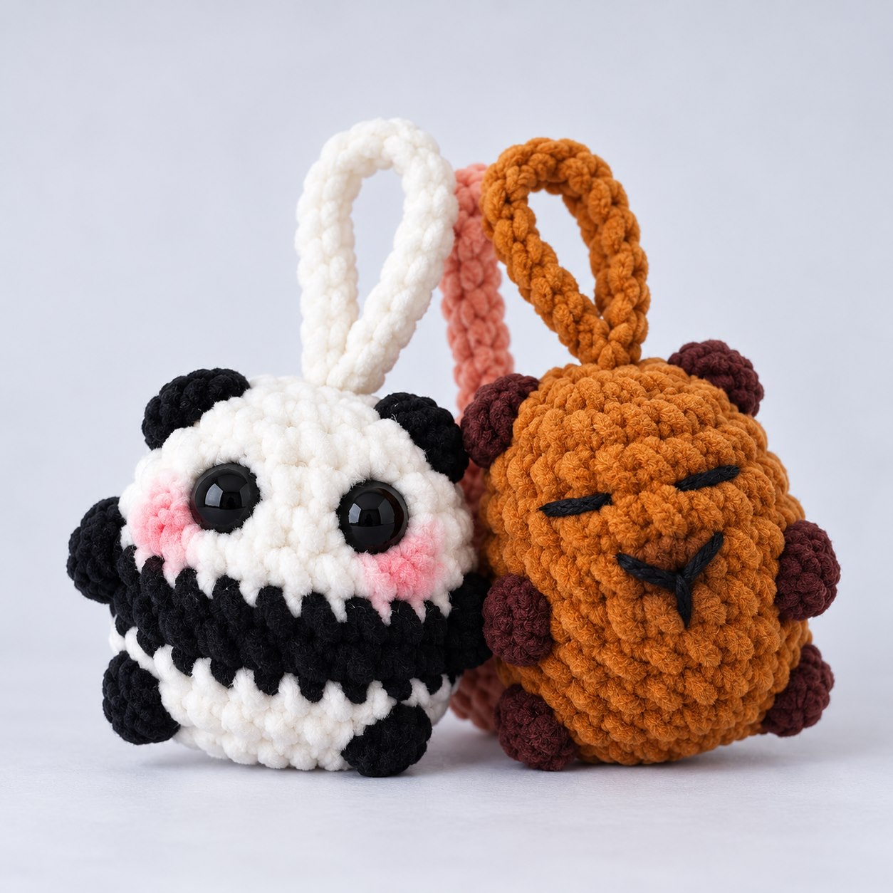 Panda Noah e Urso Sand em amigurumi, lado a lado, com alças de crochê