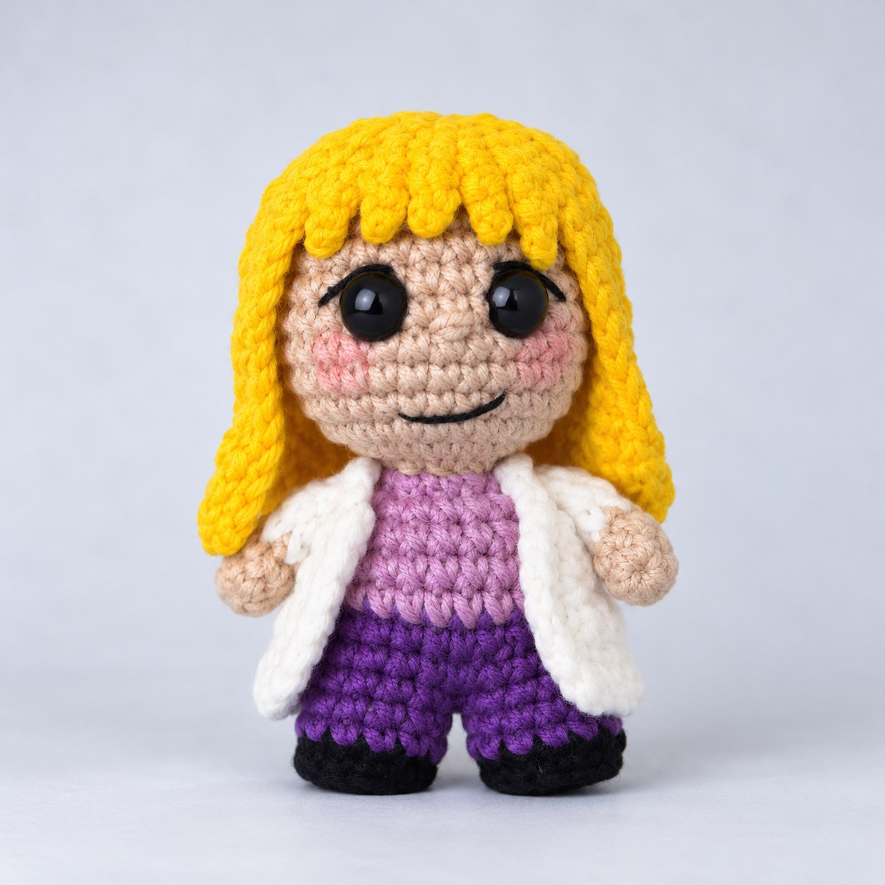 Boneca loira de amigurumi com pernas, jaleco branco e roupa roxa
